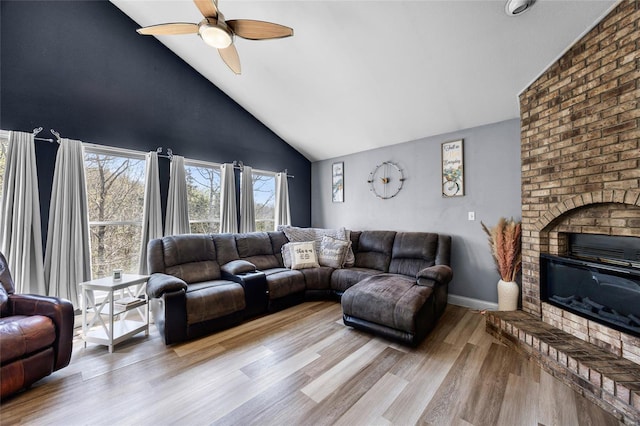 living area featuring wood finished floors, a brick fireplace, high vaulted ceiling, and ceiling fan