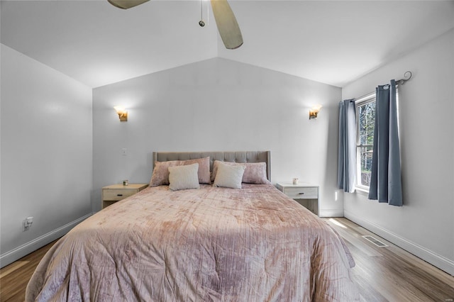 bedroom with vaulted ceiling, a ceiling fan, wood finished floors, baseboards, and visible vents