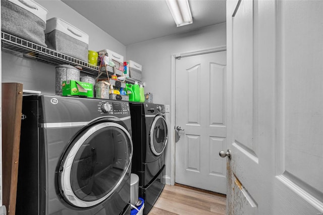 clothes washing area featuring light wood-style floors, independent washer and dryer, and laundry area
