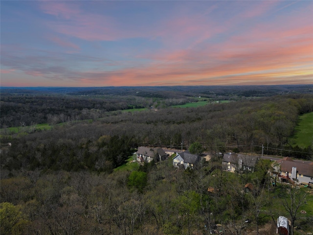 aerial view at dusk featuring a forest view