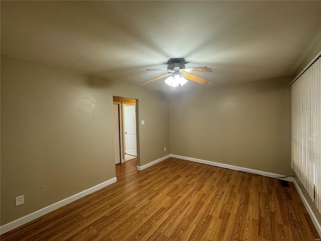 empty room featuring wood finished floors, baseboards, and ceiling fan