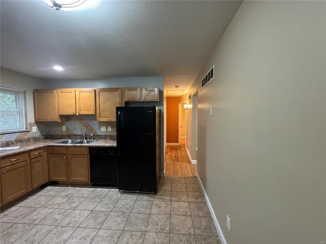 kitchen with a sink, black appliances, decorative backsplash, baseboards, and visible vents