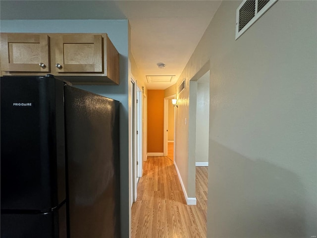 hallway with baseboards, visible vents, and light wood-style floors