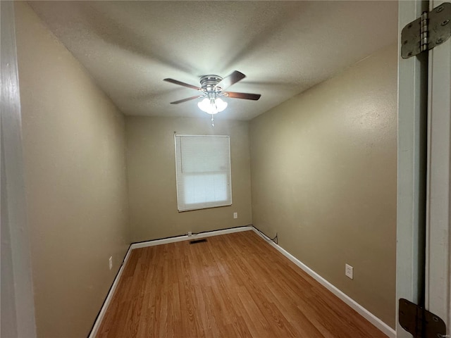 spare room featuring baseboards, wood finished floors, a textured ceiling, and ceiling fan