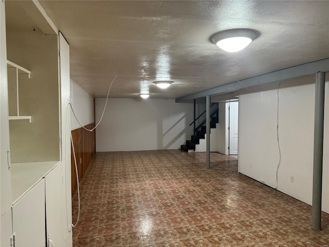 finished basement with stairway and a textured ceiling