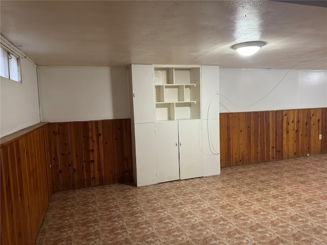 below grade area featuring wainscoting and wooden walls