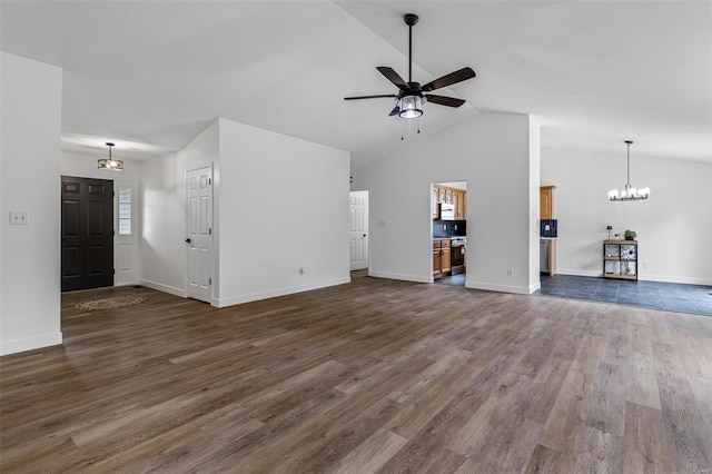unfurnished living room with ceiling fan with notable chandelier, baseboards, high vaulted ceiling, and dark wood-type flooring