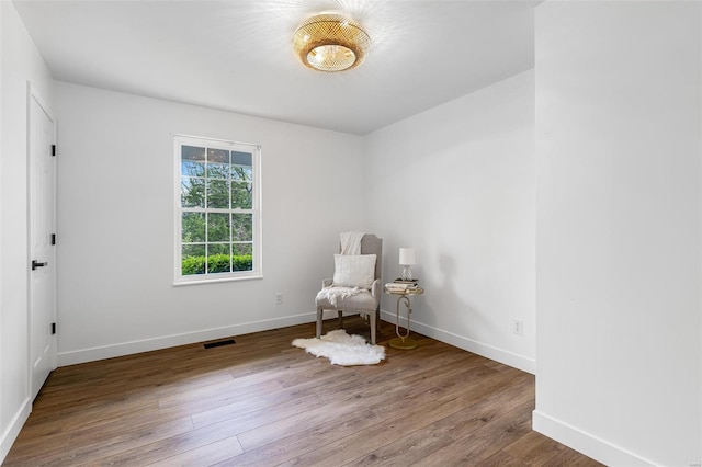 sitting room with wood finished floors, visible vents, and baseboards