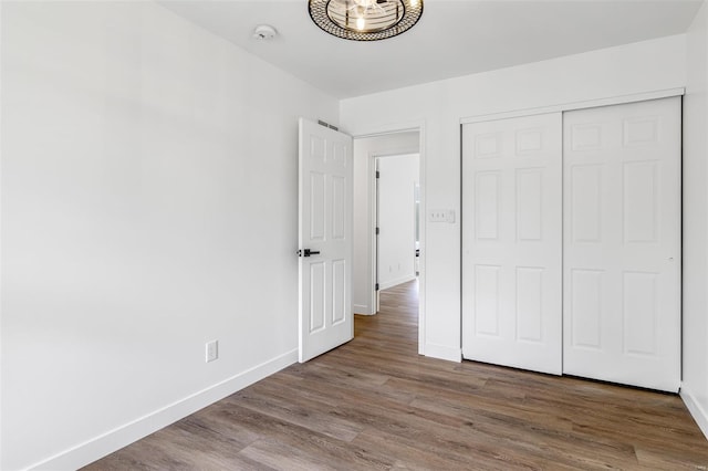 unfurnished bedroom with wood finished floors, a closet, and baseboards