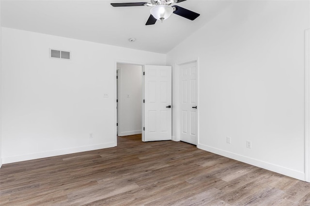 unfurnished bedroom featuring lofted ceiling, baseboards, wood finished floors, and visible vents