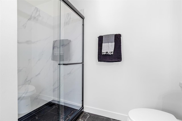 bathroom featuring marble finish floor, toilet, baseboards, and a marble finish shower