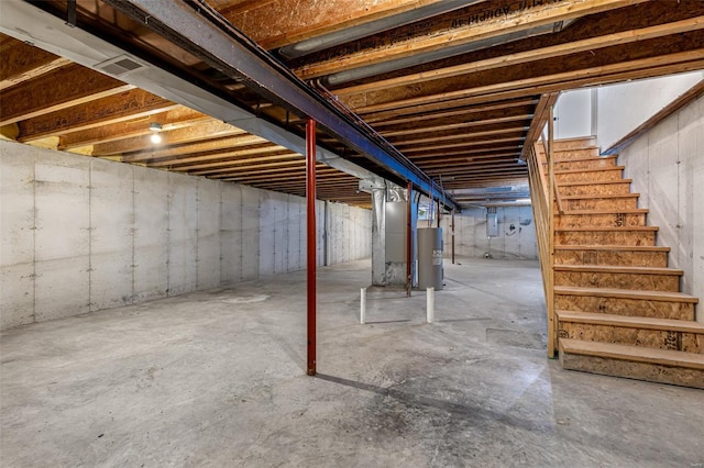 unfinished basement featuring stairs and electric water heater
