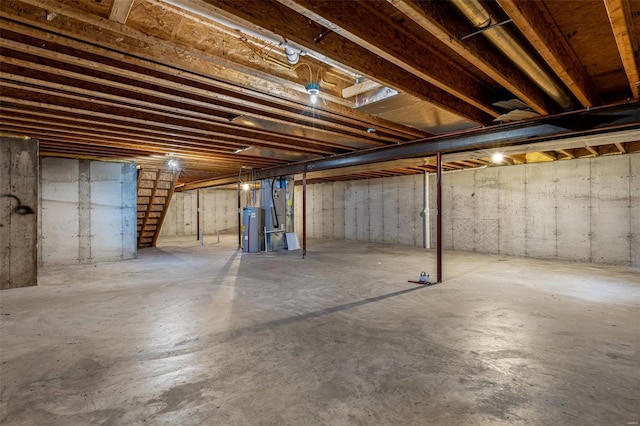 unfinished basement featuring water heater and stairway