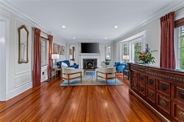 living area with plenty of natural light, ornamental molding, and wood-type flooring