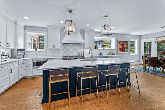 kitchen featuring a kitchen bar, tasteful backsplash, a sink, light countertops, and white cabinets