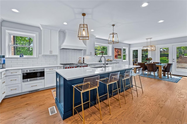 kitchen featuring visible vents, premium range hood, a kitchen bar, recessed lighting, and a sink