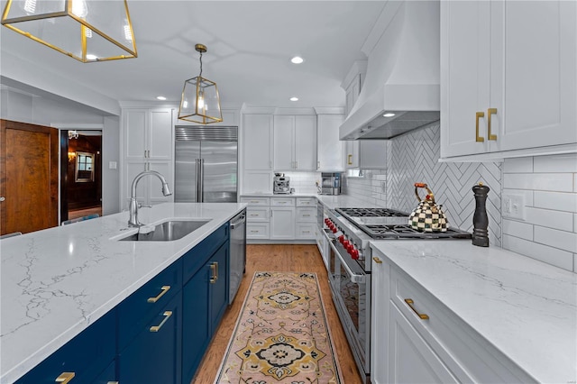 kitchen featuring blue cabinetry, high end appliances, a sink, white cabinets, and custom exhaust hood