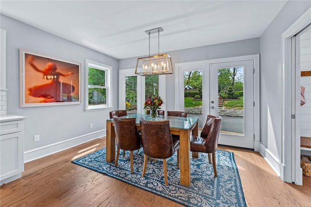 dining space featuring baseboards, a chandelier, and light wood-style floors