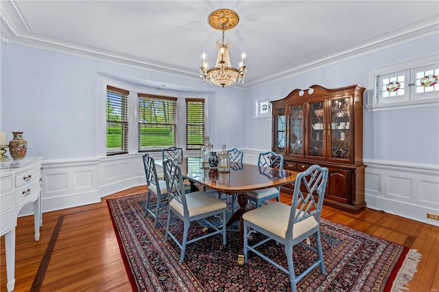 dining area featuring an inviting chandelier, ornamental molding, a wealth of natural light, and light wood finished floors