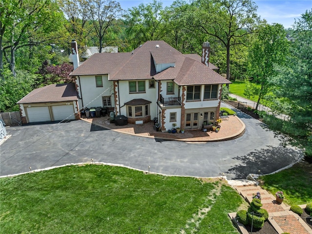 view of front of house featuring a chimney, driveway, a shingled roof, and stucco siding