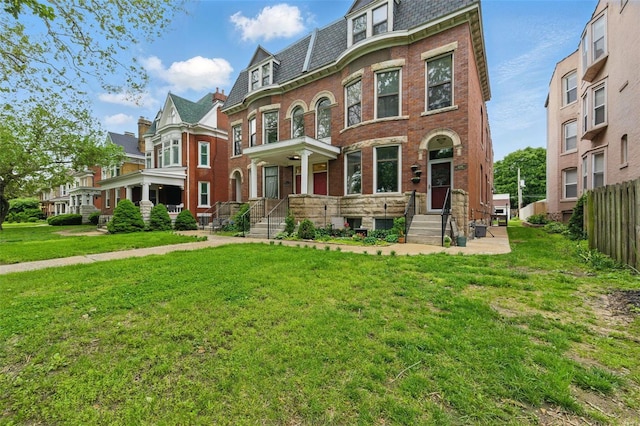 victorian home with brick siding, fence, a high end roof, mansard roof, and a front lawn