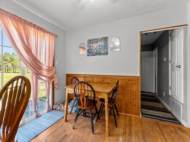 dining space featuring wood finished floors, visible vents, a ceiling fan, and wainscoting