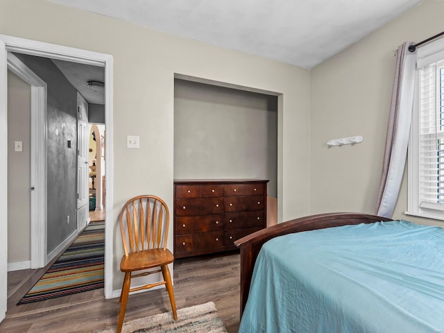 bedroom featuring multiple windows, wood finished floors, and baseboards