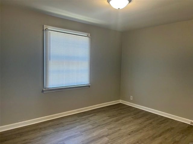 empty room with baseboards, a wealth of natural light, and dark wood finished floors