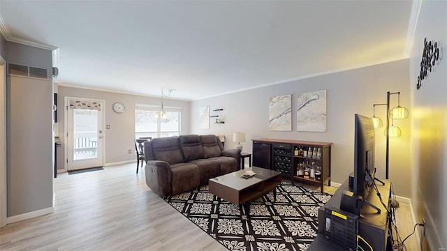 living area with wood finished floors, visible vents, crown molding, and baseboards