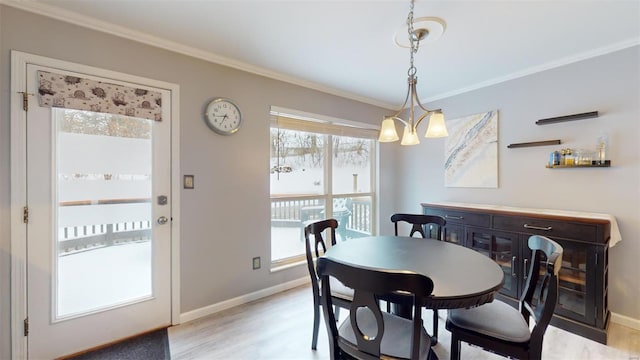 dining space featuring light wood-type flooring, baseboards, and ornamental molding