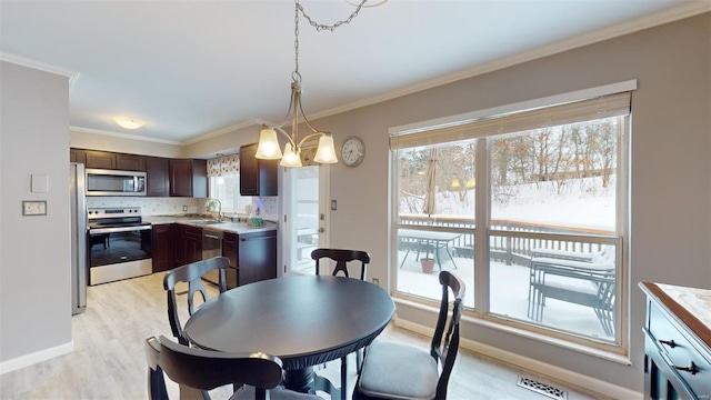 dining space with baseboards, ornamental molding, visible vents, and light wood finished floors