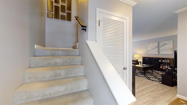 stairway with crown molding and wood finished floors