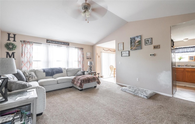 living area with light colored carpet, lofted ceiling, a ceiling fan, and a healthy amount of sunlight