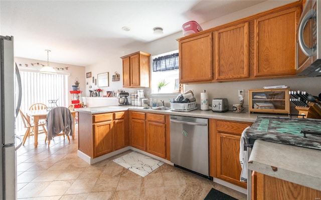 kitchen featuring a peninsula, brown cabinets, light countertops, and appliances with stainless steel finishes