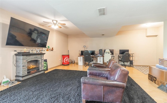 living room with ceiling fan, a fireplace, visible vents, and wood finished floors