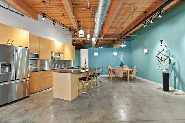 kitchen with concrete flooring, baseboards, a kitchen bar, a center island, and stainless steel appliances
