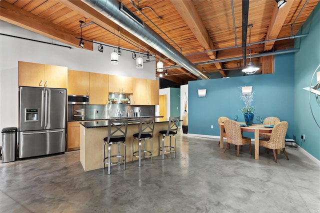 kitchen with dark countertops, appliances with stainless steel finishes, beam ceiling, finished concrete floors, and wood ceiling