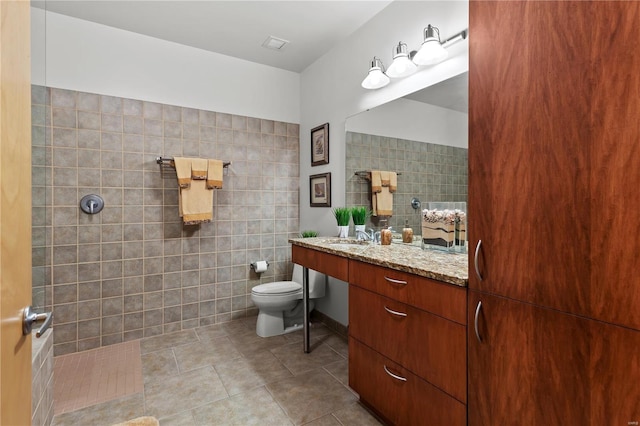 full bath with a walk in shower, toilet, tile walls, and vanity