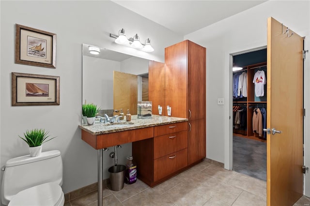 bathroom with a sink, baseboards, tile patterned floors, and toilet