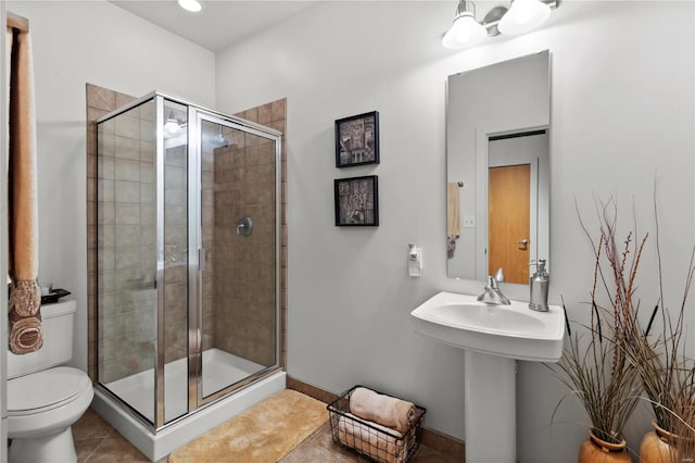 full bathroom featuring tile patterned floors, baseboards, a stall shower, and toilet