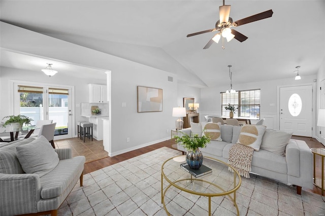 living room featuring vaulted ceiling, wood finished floors, and ceiling fan with notable chandelier