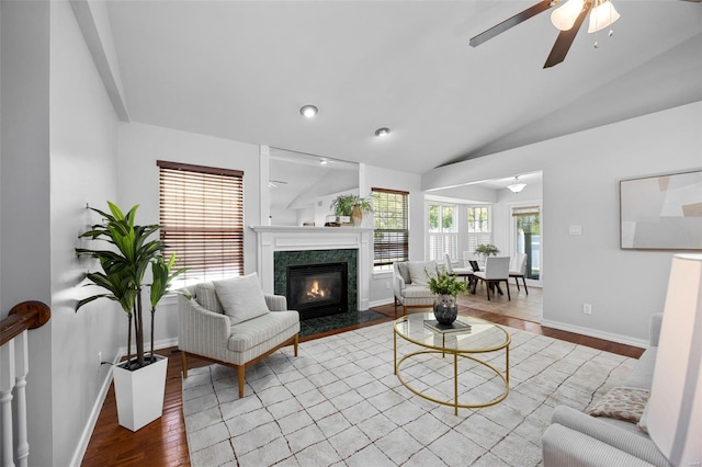 living room with vaulted ceiling, baseboards, a premium fireplace, wood finished floors, and ceiling fan