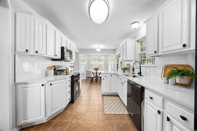 kitchen with a sink, white cabinetry, and black appliances