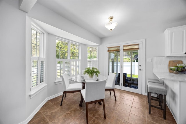 dining room featuring a wealth of natural light, dark tile patterned floors, and baseboards