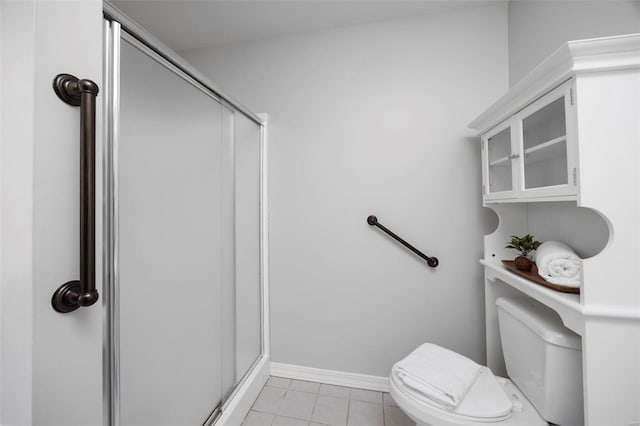 bathroom with a shower stall, toilet, baseboards, and tile patterned floors