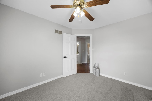 carpeted spare room with baseboards, visible vents, and ceiling fan