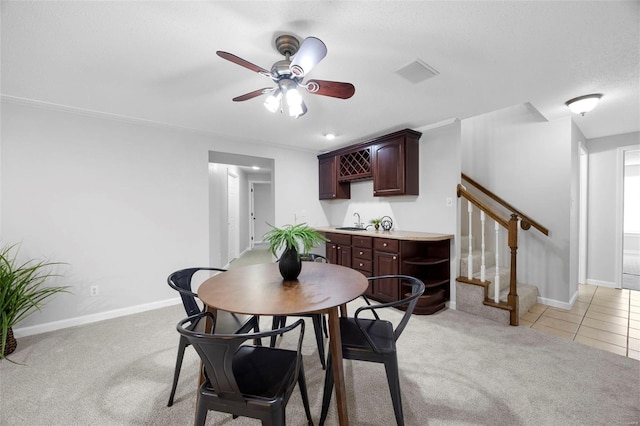 dining space featuring baseboards, indoor wet bar, stairway, and a ceiling fan