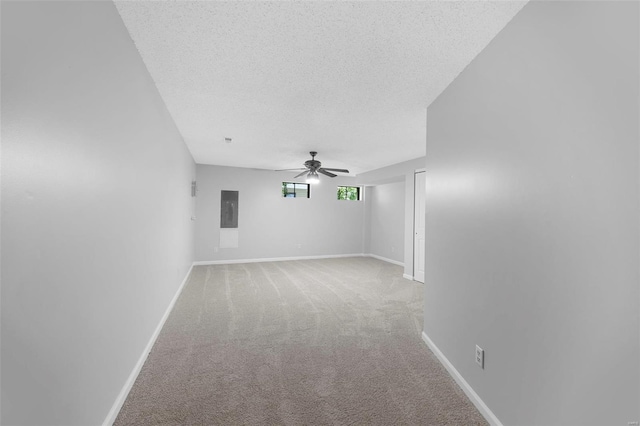 empty room featuring light colored carpet, ceiling fan, baseboards, and a textured ceiling