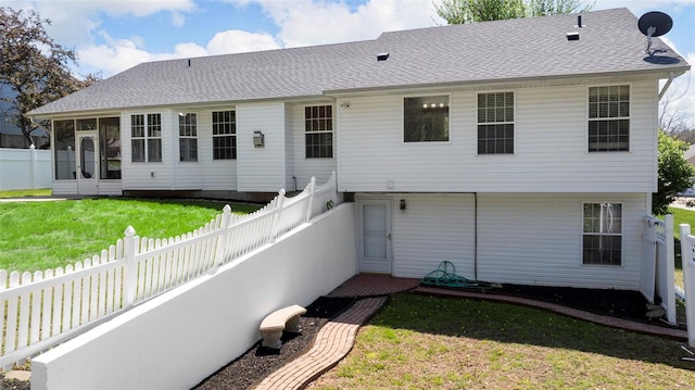 rear view of house with a fenced backyard, roof with shingles, a yard, and a sunroom