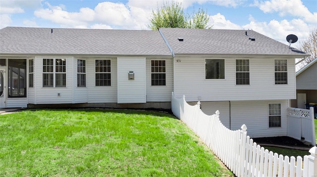 rear view of house with a yard, roof with shingles, and a fenced backyard